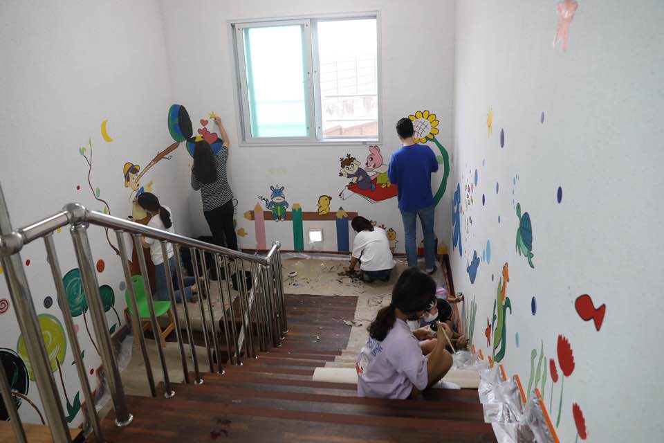 학교 건물 내벽에 벽화를 그리는 학생들의 모습