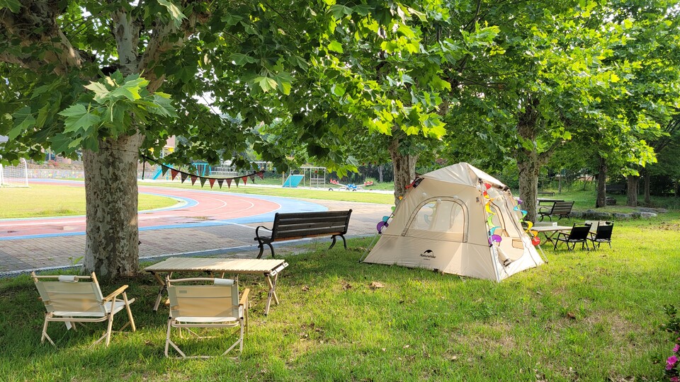 학교 운동장 플라타너스 나무 주변에 텐트, 의자, 테이블 등으로 쉼터를 조성해두었다. 